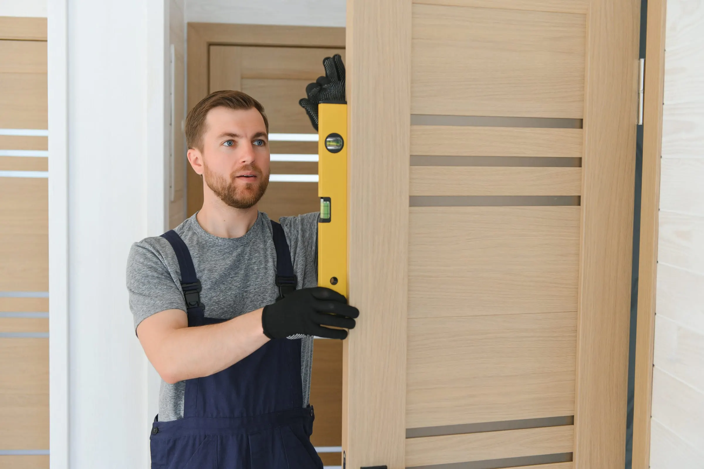 Carpintero con cinturón de herramientas cortando un tablero de madera con sierra circular en una vivienda en obra