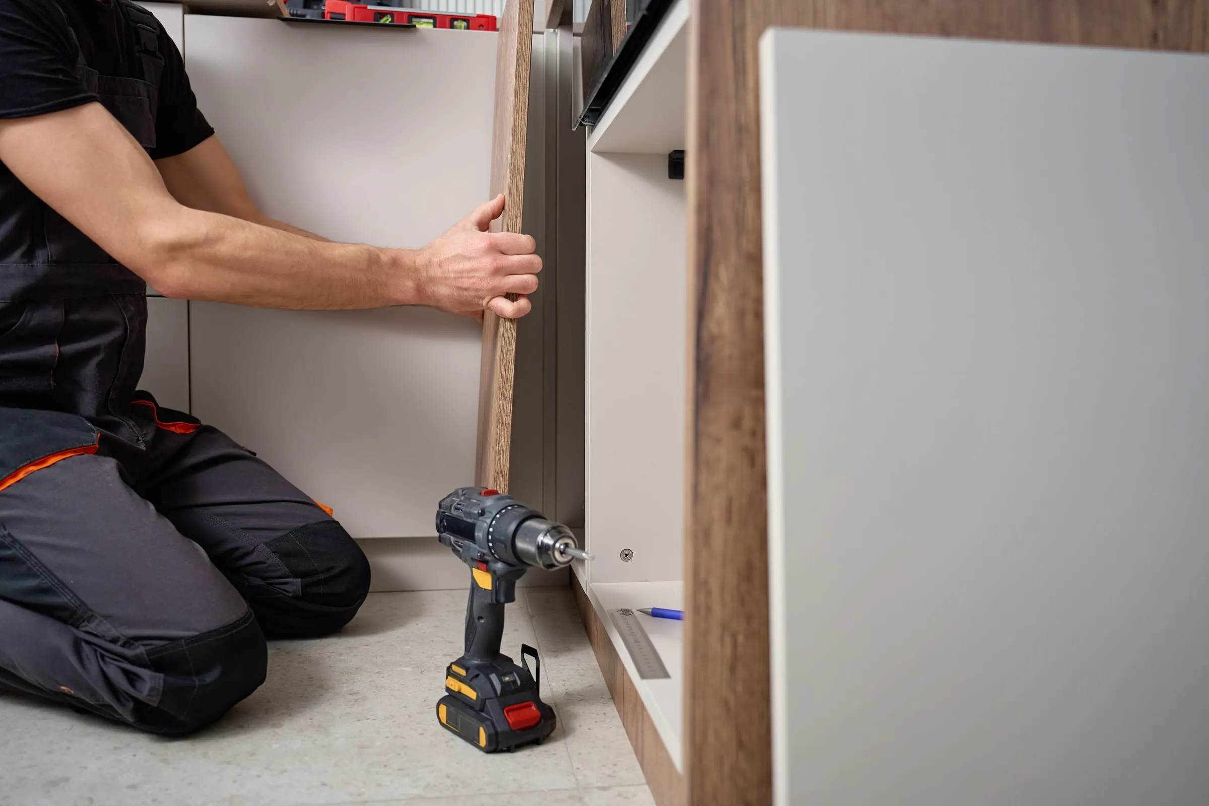 Carpintero con cinturón de herramientas cortando un tablero de madera con sierra circular en una vivienda en obra