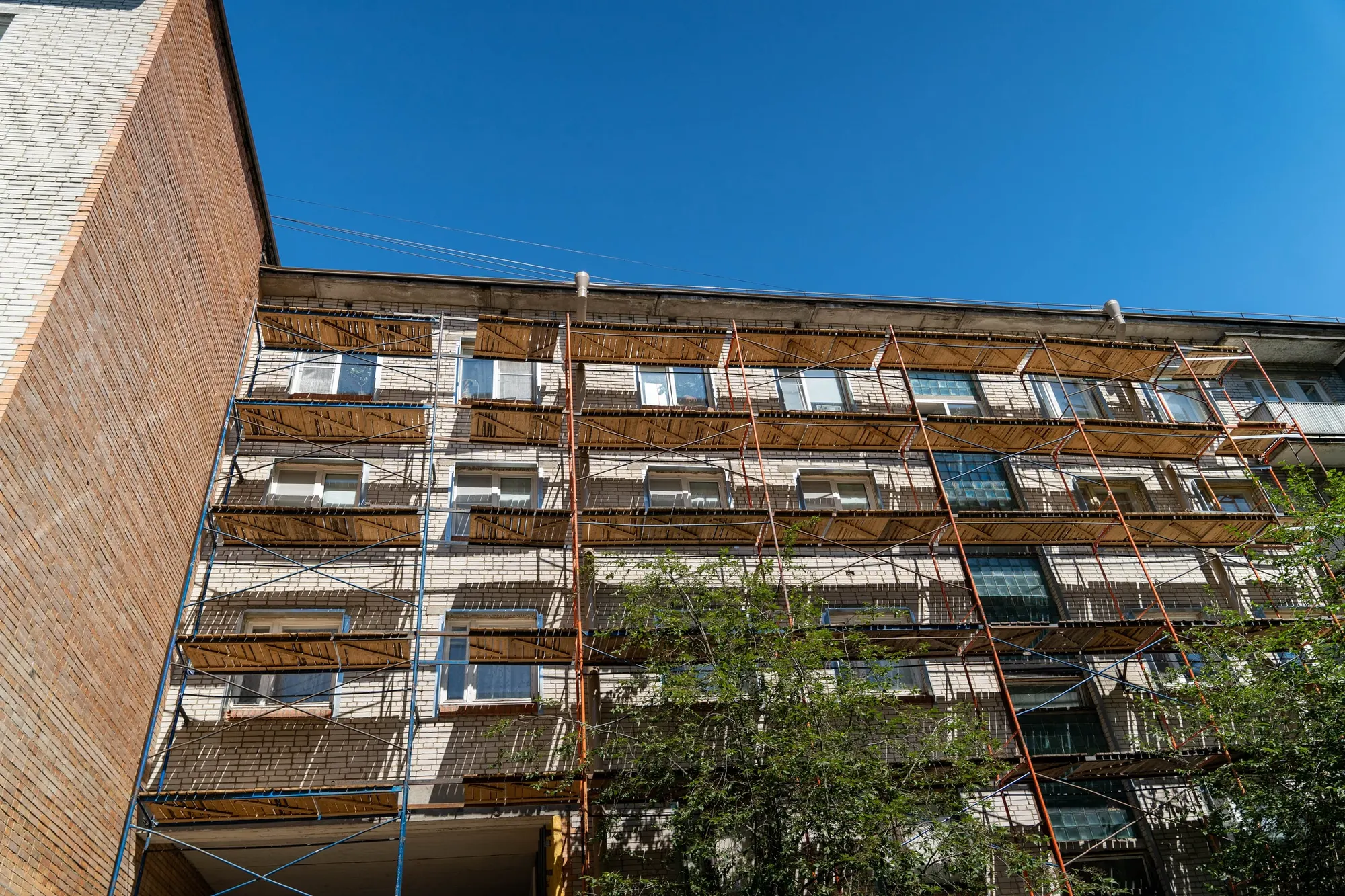 Edificio residencial de ladrillo cubierto de andamios durante la rehabilitación de su fachada